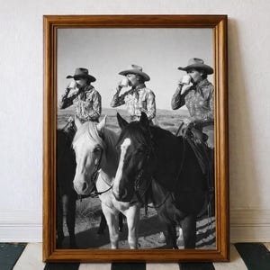 Può includere: Stampa incorniciata in bianco e nero con tre cowgirl a cavallo, ognuna che beve da una tazza. I cavalli sono di vari colori. Le cowgirl indossano cappelli e camicie fantasia. Lo sfondo mostra un paesaggio desertico.