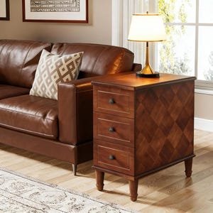 May include: A wooden side table with three drawers and a diamond pattern on the front. The table is brown and has a lamp on top. The table is next to a brown leather sofa.