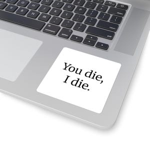 Op de afbeelding: Een witte vierkante sticker met de tekst "You die, I die" in het zwart, geplaatst op een laptop. De laptop heeft een zilveren behuizing en een zwart toetsenbord.