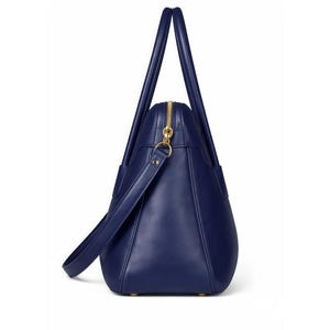 May include: A navy blue tote bag with a gold zipper and handles. The bag has a shoulder strap and a structured design. The bag is made of a smooth material and has a classic, elegant look.