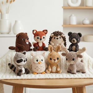 May include: A collection of eight crocheted woodland animal figurines. The animals include a beaver, fox, hedgehog, bear, raccoon, owl, rabbit, and moose. Each animal is made with yarn in various colors and has detailed features.