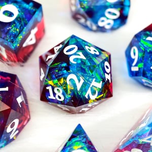 Può includere: Un assortimento di dadi poliedrici con un design colorato e iridescente. I dadi presentano una miscela di tonalità blu, verdi e rosse con numeri bianchi. Adatti per giochi di ruolo da tavolo.