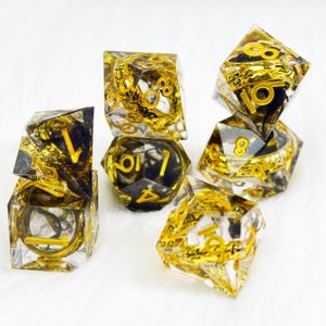 Puede incluir: Juego de siete dados poliédricos con base de resina transparente, detalles negros y números y diseños dorados. Los dados están diseñados para juegos de rol de mesa.