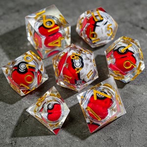 Op de afbeelding: Set van zeven heldere harsdobbelstenen met een rood-wit ontwerp en goudkleurige cijfers. De dobbelstenen hebben een uniek ontwerp met een rood-witte bal erin. Perfect voor tabletop games.