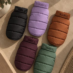 Peut inclure: Cinq gilets matelassés pour animaux de compagnie en noir, lavande, marron, violet foncé et vert sauge. Chaque gilet sans manches présente un col haut avec le texte Waudog imprimé en noir, des coutures horizontales et un tissu mat lisse.