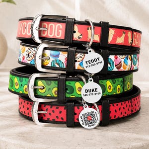 Puede incluir: Una pila de cuatro collares para perro con bordes de piel sintética negra y hebillas plateadas. Los patrones incluyen carlinos sobre fondo rojo, donuts y cupcakes sobre blanco, aguacates verdes y rodajas de sandía. Cada collar tiene una placa metálica.