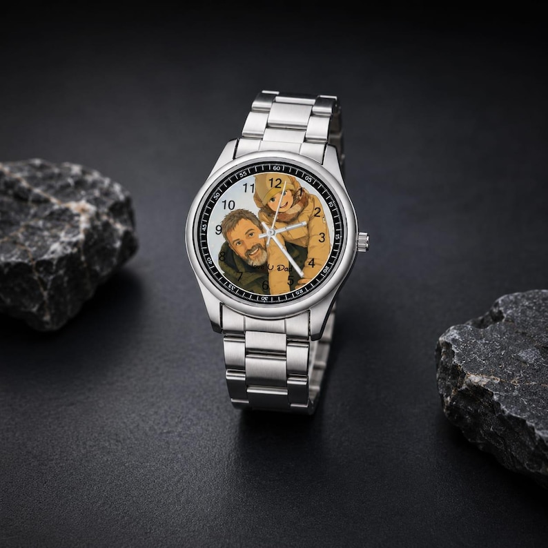 Puede incluir: Un reloj de pulsera anal&oacute;gico de tono plateado con correa de eslabones met&aacute;licos. La esfera presenta una ilustraci&oacute;n personalizada de una persona cargando a un ni&ntilde;o en su espalda, con n&uacute;meros negros y finas manecillas plateadas sobre fondo claro.