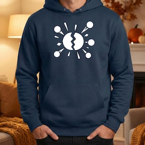 May include: Navy blue hoodie featuring a white graphic of a cracked sphere with radiating lines and circles. The hoodie has a front pocket and a drawstring hood. The design is centered on the chest.