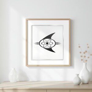 May include: Framed black and white print with a retro-futuristic atom symbol design. The artwork is set against a white background, framed in light wood. The print is displayed on a wooden surface with white vases. The frame is approximately 30 cm x 40 cm.
