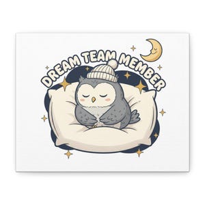 May include: A canvas print featuring a cartoon owl wearing a knit cap, resting on a pillow. The owl is gray with a white belly and closed eyes. The text "DREAM TEAM MEMBER" arches above the owl, with stars and a crescent moon in the background.