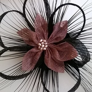 May include: A black feather hair comb with a pink flower accent. The flower has a pearl center.