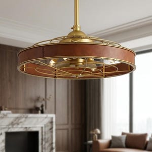May include: A circular ceiling fan light fixture featuring a central brass-toned metal rod and a wide, drum-shaped frame. The frame is wrapped in brown leather-like material and enclosed by a gold-toned metal wire cage with internal light bulbs.