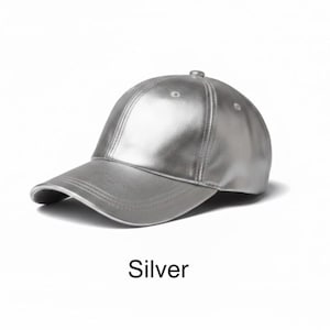 May include: Silver baseball cap with a curved brim. The cap is made of a shiny, metallic material. The word "Silver" is printed below the cap.