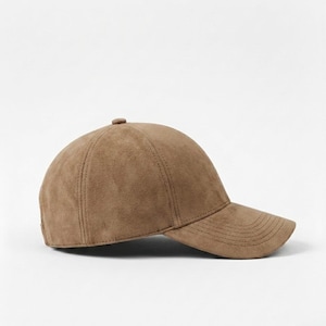K&ouml;nnte beinhalten: Braune Baseballkappe mit gebogenem Schirm. Die Kappe besteht aus einem Wildleder-&auml;hnlichen Material und hat einen Knopf oben. Der Hut ist einfarbig und hat einen klassischen, l&auml;ssigen Stil.