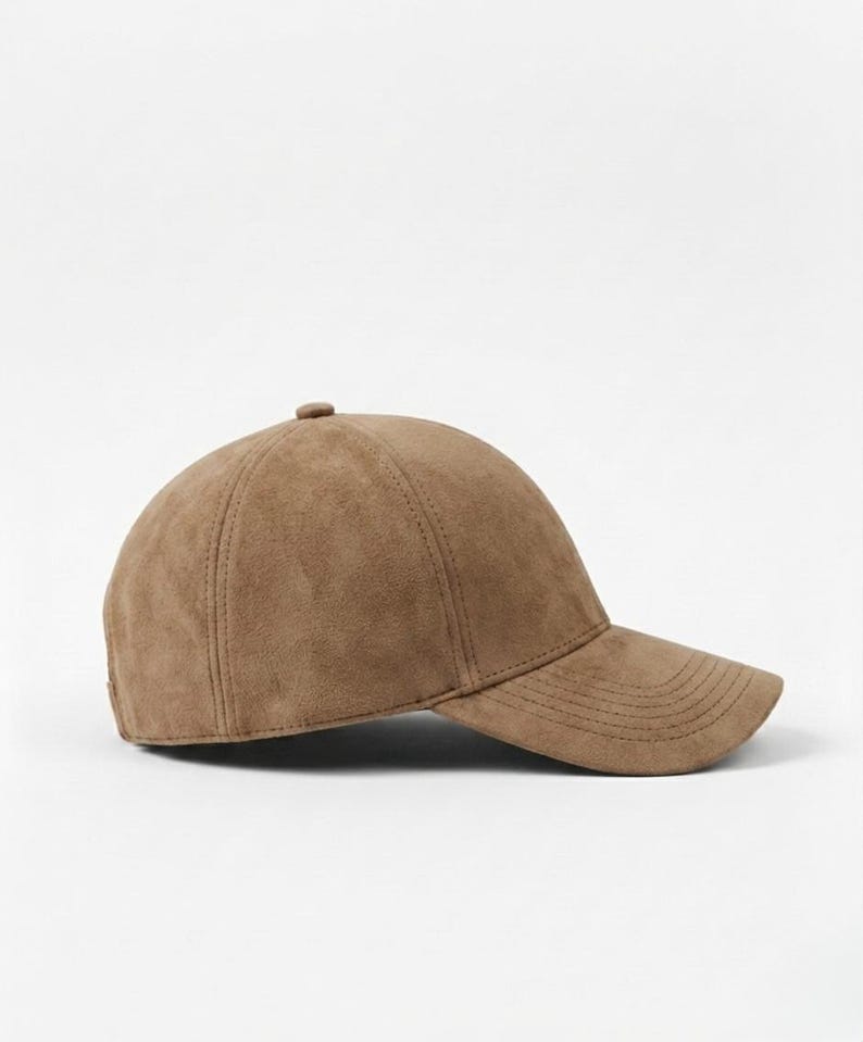 K&ouml;nnte beinhalten: Braune Baseballkappe mit gebogenem Schirm. Die Kappe besteht aus einem Wildleder-&auml;hnlichen Material und hat einen Knopf oben. Der Hut ist einfarbig und hat einen klassischen, l&auml;ssigen Stil.