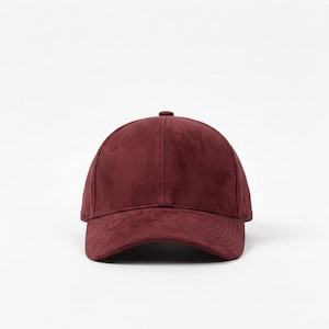 K&ouml;nnte beinhalten: Burgunderfarbene Baseballkappe mit gebogenem Schirm. Die Kappe besteht aus einem Wildleder-&auml;hnlichen Material und hat einen Knopf oben. Der Hut ist einfarbig und hat einen klassischen, l&auml;ssigen Stil.