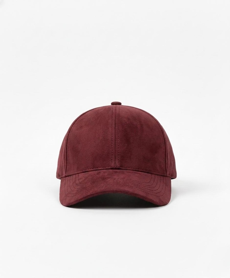 K&ouml;nnte beinhalten: Burgunderfarbene Baseballkappe mit gebogenem Schirm. Die Kappe besteht aus einem Wildleder-&auml;hnlichen Material und hat einen Knopf oben. Der Hut ist einfarbig und hat einen klassischen, l&auml;ssigen Stil.