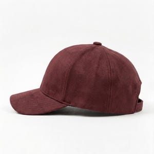 K&ouml;nnte beinhalten: Burgunderfarbene Baseballkappe mit gebogenem Schirm. Die Kappe besteht aus einem weichen, Wildleder-&auml;hnlichen Material und hat einen kleinen Knopf oben. Ein verstellbarer Riemen ist hinten sichtbar.