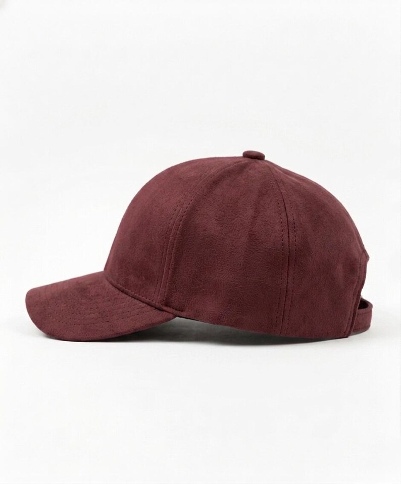 K&ouml;nnte beinhalten: Burgunderfarbene Baseballkappe mit gebogenem Schirm. Die Kappe besteht aus einem weichen, Wildleder-&auml;hnlichen Material und hat einen kleinen Knopf oben. Ein verstellbarer Riemen ist hinten sichtbar.