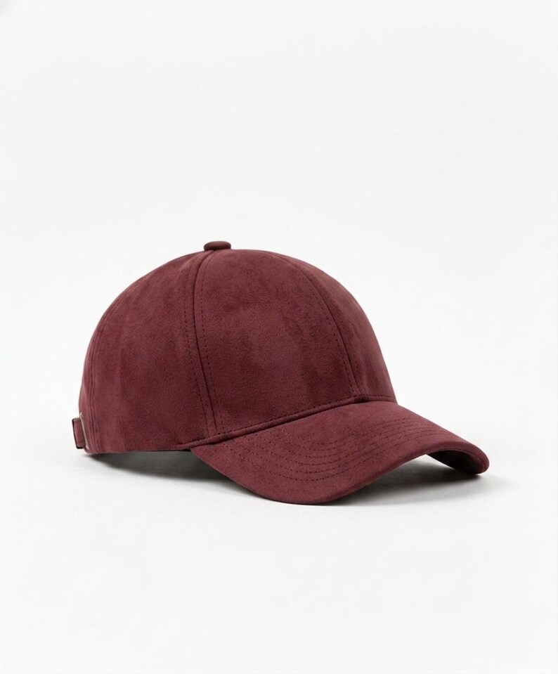 K&ouml;nnte beinhalten: Burgunderfarbene Baseballkappe mit gebogenem Schirm. Die Kappe besteht aus einem weichen, Wildleder-&auml;hnlichen Material und hat einen kleinen verstellbaren Riemen am R&uuml;cken. Klassisches Sechs-Panel-Design und Knopf oben.