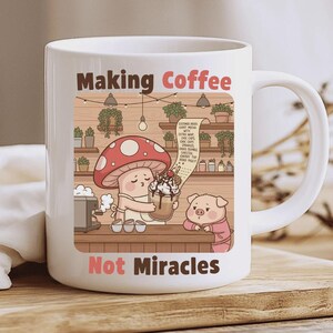 Puede incluir: Taza de cerámica blanca con una ilustración de dibujos animados. La imagen muestra un hongo preparando café para un cerdo. El texto en la taza dice "Making Coffee Not Miracles". La escena de la cafetería incluye un menú y luces colgantes.