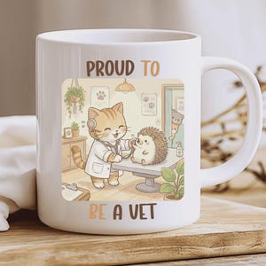Puede incluir: Taza de cerámica blanca con una ilustración de dibujos animados de un gato veterinario examinando un erizo. La imagen incluye el texto "PROUD TO BE A VET" en letras marrones y beige. La taza tiene un asa curva.