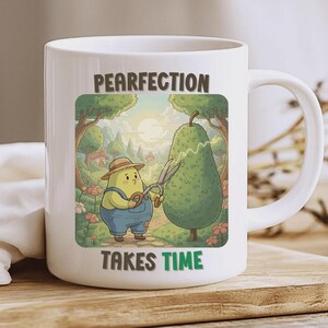 Puede incluir: Taza de cerámica blanca con una ilustración caprichosa. El diseño presenta un personaje en forma de pera con un mono y un sombrero de paja, recortando un topiario en forma de pera con tijeras. El texto dice "PEARFECTION TAKES TIME".