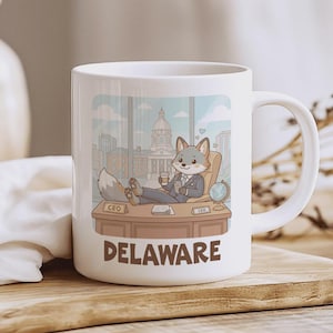Puede incluir: Taza de cerámica blanca con un zorro de dibujos animados con traje, relajándose en un escritorio con la palabra "DELAWARE" debajo. El zorro sostiene una taza de café. Un globo terráqueo y un paisaje urbano son visibles en el fondo.