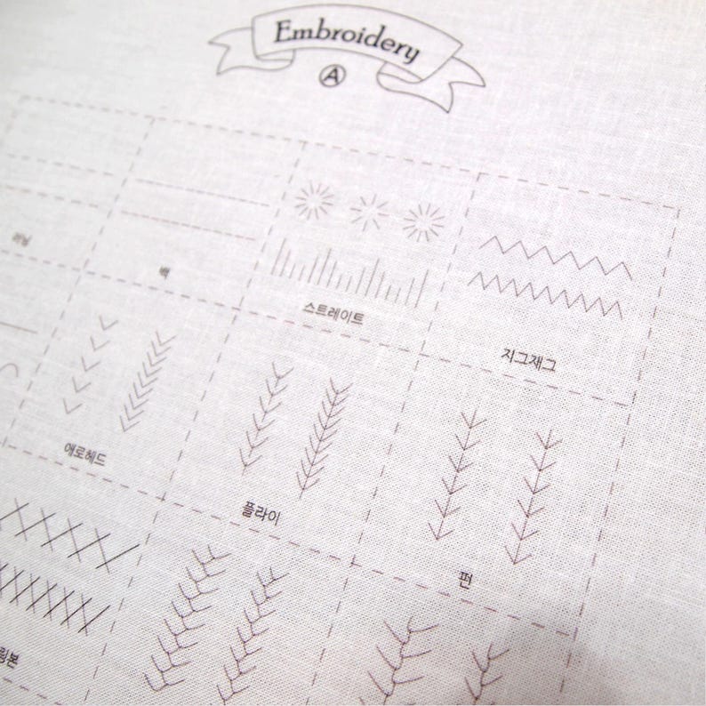 May include: A close-up of a white fabric with various embroidery stitch examples. The word "Embroidery" is at the top. Stitch types include straight, zigzag, and others, with Korean text labels. The stitches are in a dark brown color.