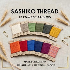 May include: Twelve spools of Sashiko thread in vibrant colours, each wrapped on a cardboard bobbin. The set includes white, grey, green, olive, dark grey, yellow, orange, red, blue, navy, purple, and multicoloured thread. Text reads SASHIKO THREAD.
