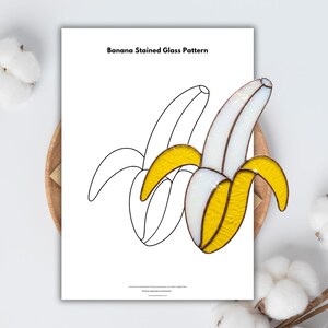 Può includere: Un motivo a vetrata di banana con buccia gialla e polpa bianca, su sfondo bianco. Il testo "Banana Stained Glass Pattern" è visualizzato nella parte superiore della pagina. L'immagine è su un vassoio di legno.