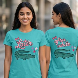 May include: Teal t-shirts with a cartoon alligator design. The front of the shirt says "Later" in pink script with a bow and stars. The back of the shirt says "after while" with a bow and stars.