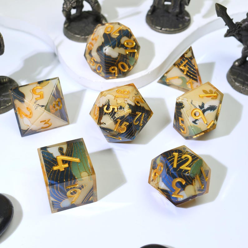 May include: A selection of multi-sided dice with a distinctive design. The dice are made of clear resin with a blue, green, and gold pattern. The numbers are gold. Metal figurines are in the background.