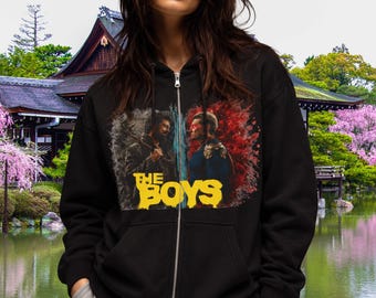 May include: A black zip-up hoodie featuring a graphic print of two characters facing each other, one on a grey background and one on a red background, with the yellow text "THE BOYS" printed prominently below the figures on the front of the garment.