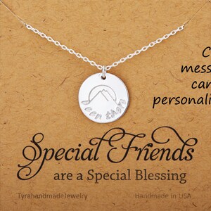 May include: Silver necklace with a round pendant featuring a mountain silhouette and the words "Been there" engraved on it. The necklace is displayed on a brown card with the text "Special Friends are a Special Blessing".
