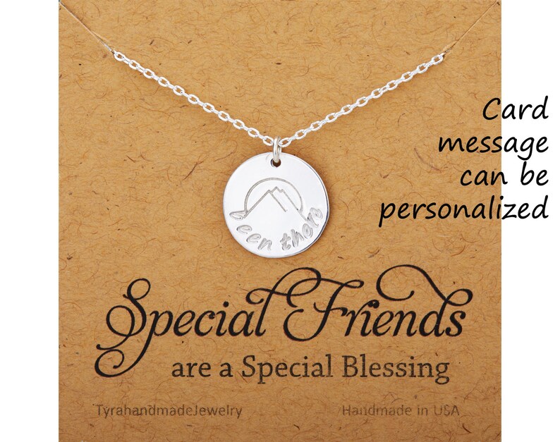 May include: Silver necklace with a round pendant featuring a mountain silhouette and the words "Been there" engraved on it. The necklace is displayed on a brown card with the text "Special Friends are a Special Blessing".