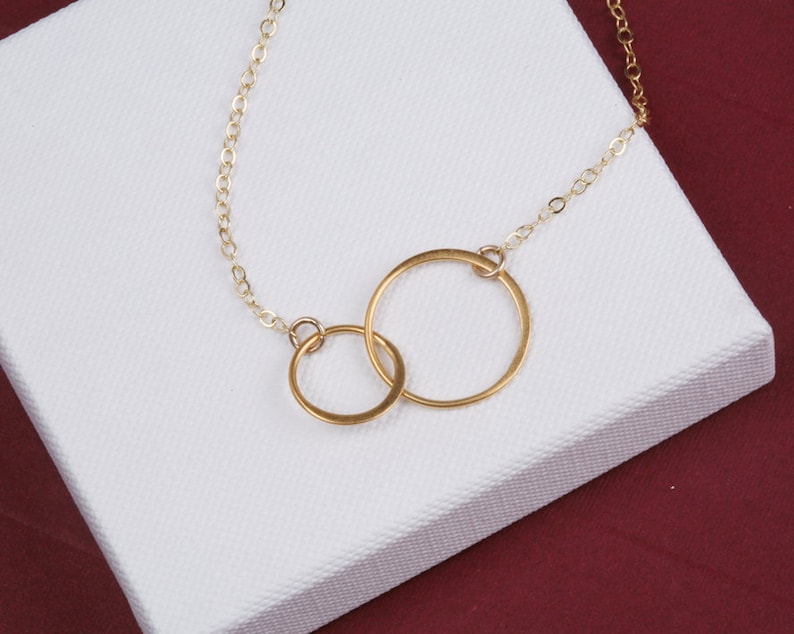 May include: A gold chain necklace with two interlocking circles as a pendant.