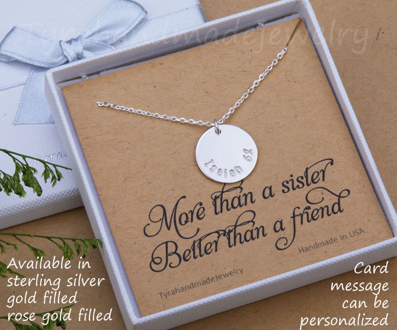 May include: A silver necklace with a round pendant that says "More than a sister, Better than a friend." The pendant is engraved with the name "Isaiah 64". The necklace is in a white box with a brown paper insert.
