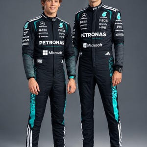 Op de afbeelding: Twee zwarte raceoveralls met turquoise accenten, witte strepen en diverse sponsorlogo's waaronder Petronas, Microsoft en IWC. De overalls hebben hoge kragen, lange mouwen en worden gecombineerd met felblauw sportschoeisel.