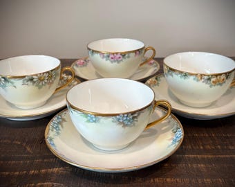 Juego de 4 tazas y platillos de té O&E.G. Royal Austria con diseño floral y ribete dorado.