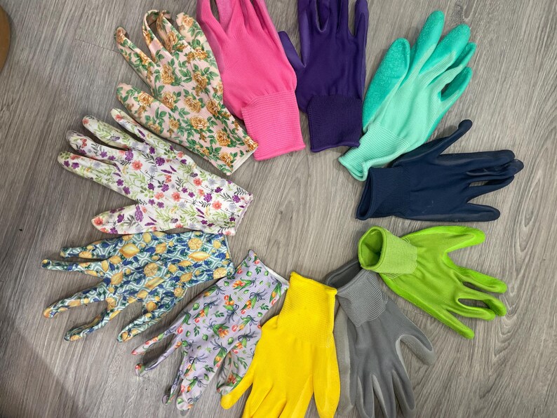 May include: A collection of gardening gloves in various colors and patterns. The gloves include floral prints, solid pink, purple, teal, navy, yellow, and gray. The gloves are arranged in a circular pattern on a wooden surface.