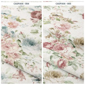 May include: Two fabric samples with a floral pattern. The design features large, detailed roses in shades of pink, red, and cream, with accents of blue and green foliage. The fabric has a light-colored background, and the text "CASPIAN - 004" and "CASPIAN - 005" is visible.