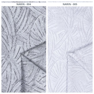 May include: Two fabric samples labeled NARIN-004 and NARIN-005. The left sample is a medium gray textile with a raised, textured fan-like pattern. The right sample is a light white textile featuring the same raised, textured fan-like design.