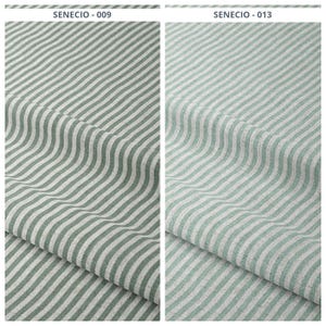 Puede incluir: Dos muestras de tela con un patrón de rayas. Las rayas son de color verde claro alternando con blanco. La tela está doblada, mostrando la textura y la caída del material. La parte superior de la imagen tiene el texto "SENECIO - 009" y "SENECIO - 013".