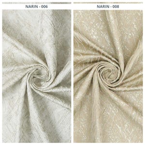 May include: Two fabric swatches labeled NARIN-006 and NARIN-008. The left swatch is a white fabric with a textured, light gray abstract pattern. The right swatch is a beige fabric with a textured, metallic gold abstract pattern. Both fabrics are gathered in a central spiral, showcasing a crinkled, dimensional surface texture.