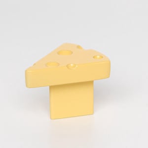 Puede incluir: Un objeto amarillo con forma de queso con una base rectangular y una parte superior triangular. La parte superior tiene varios agujeros circulares. La palabra "Yellow" está en la esquina superior izquierda.