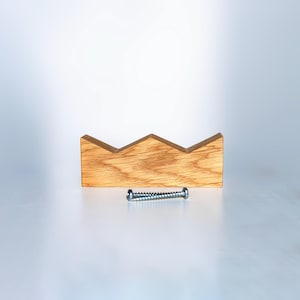Peut inclure: Un objet en forme de couronne en bois avec un grain de bois naturel. Une vis argentée est positionnée en dessous de la couronne. La couronne a un bord supérieur dentelé et est probablement un objet décoratif.