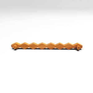 May include: A long, horizontal wooden cabinet pull featuring a repeating geometric diamond pattern along its length. The handle is crafted from light-toned wood with a visible grain and includes two cylindrical mounting points at each end.