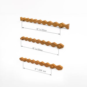 Può includere: Tre maniglie per armadietti in legno marrone chiaro con un motivo geometrico a rombi ripetuto. Due maniglie misurano 410 mm e una maniglia misura 308 mm, come indicato dalle linee di quota tecniche stampate sull'immagine.