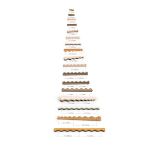 Puede incluir: Una colección de piezas de adorno festoneado de madera dispuestas verticalmente en tamaño creciente. Cada pieza está etiquetada con su longitud en pulgadas y milímetros, que van desde 3 pulgadas (76 mm) hasta 9 pulgadas (229 mm) para varios segmentos.
